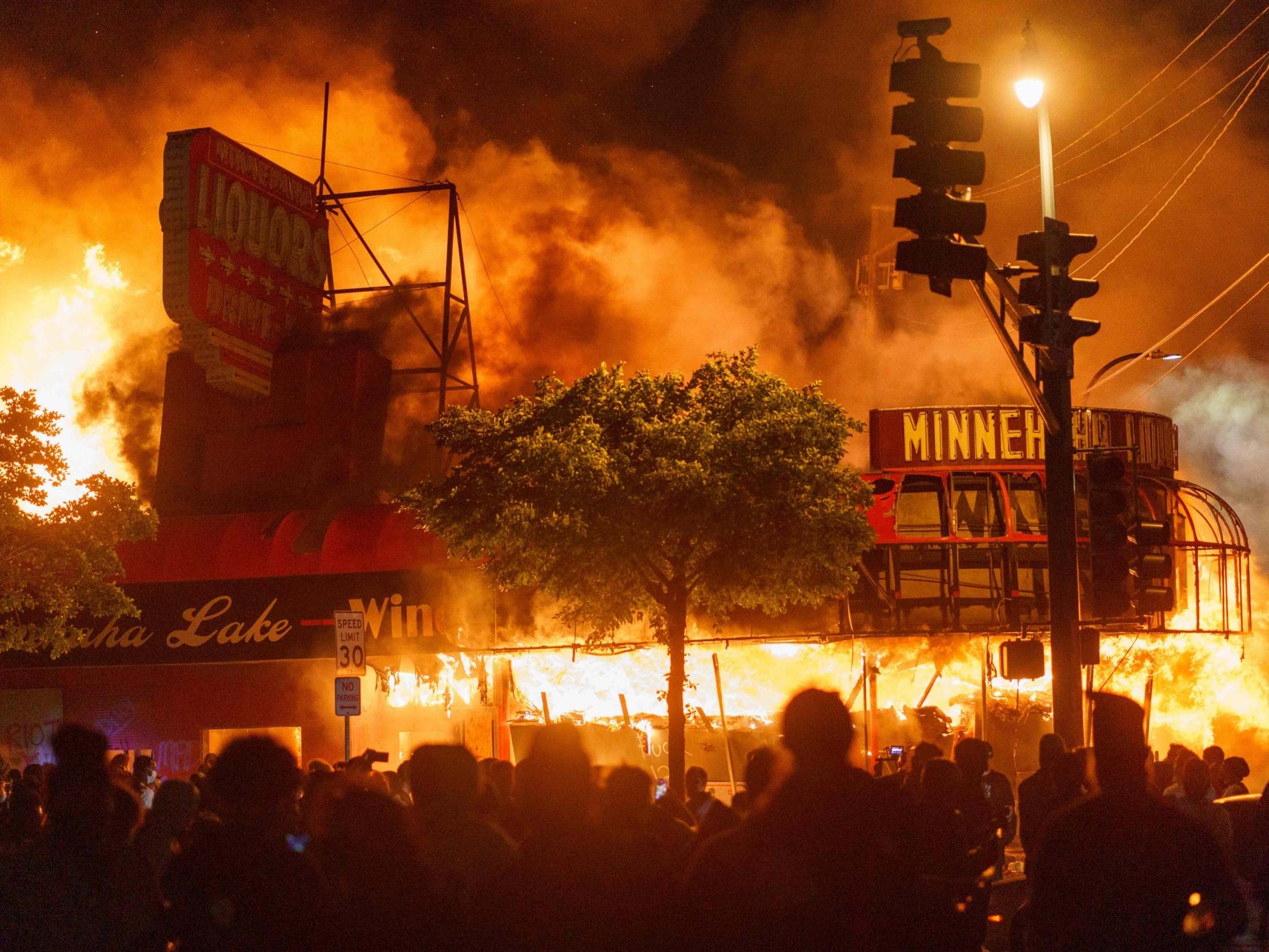 Protesters gather in front of a liquor store in flames near the police building in Minneapolis