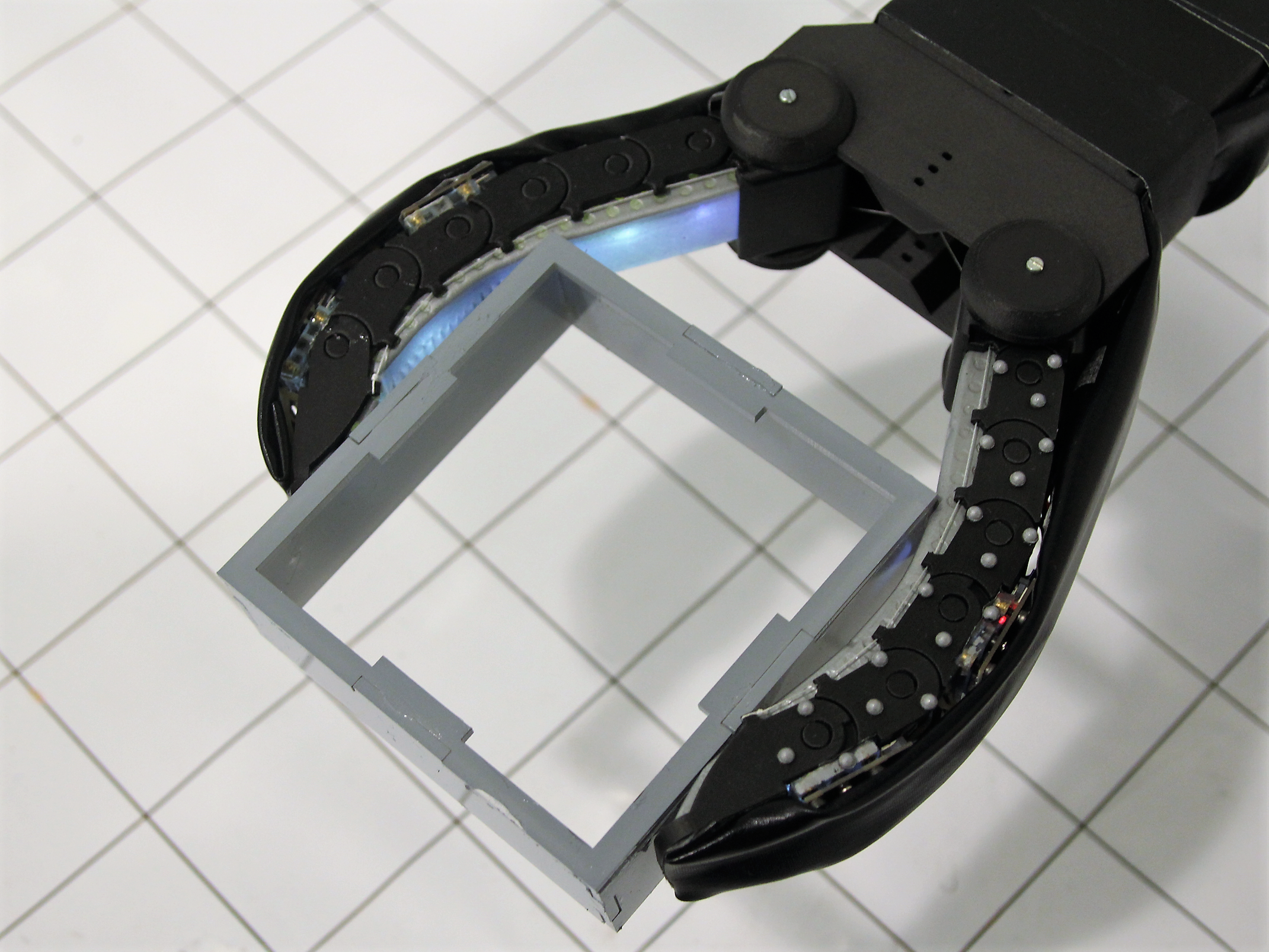 The robot hand uses squishy and flexible materials to delicately grip glass