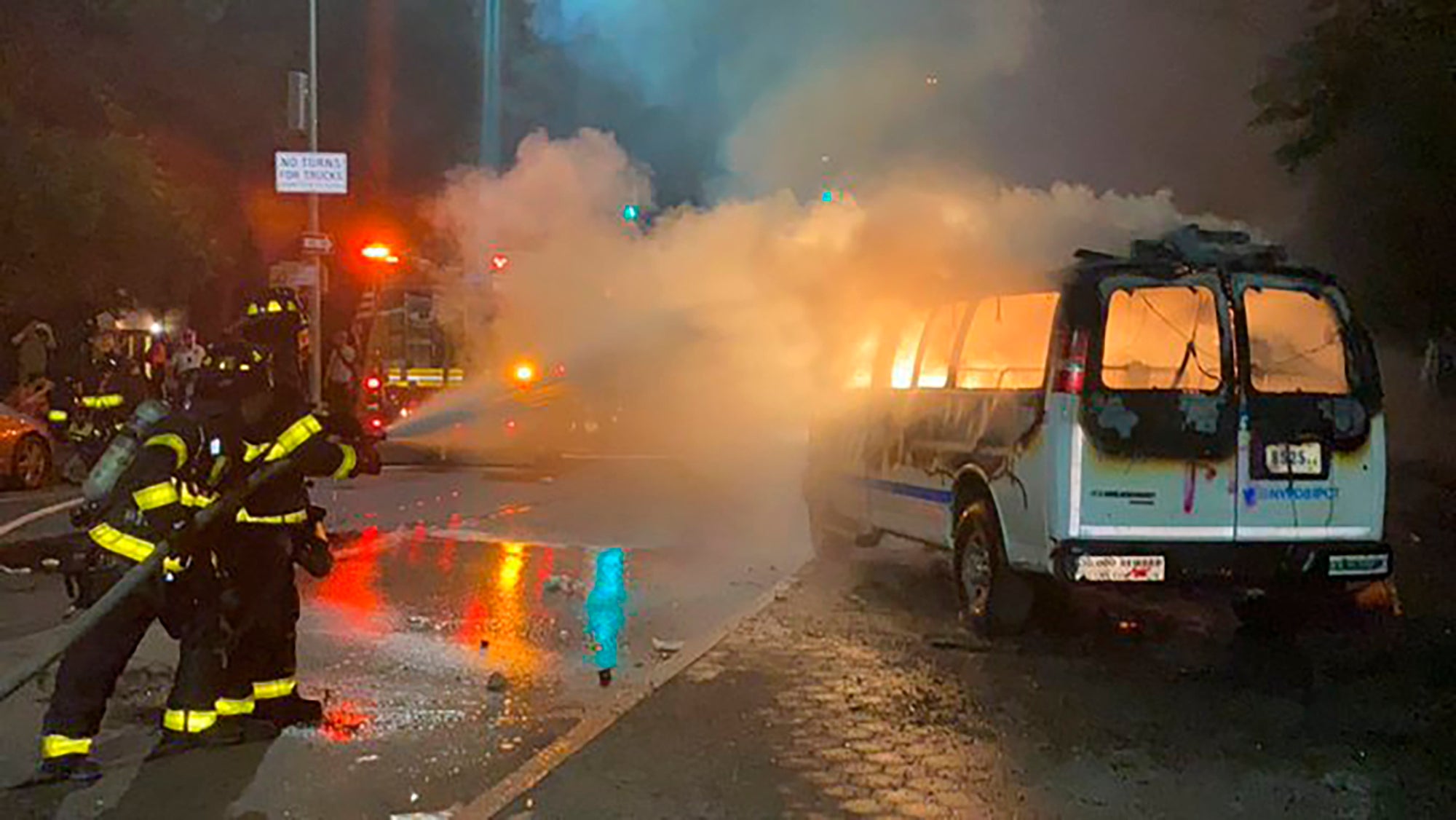 In this photo provided by Khadijah, firefighters work to contain the flames from a New York City Police Department van ablaze, Friday, May 29, 2020, in the Brooklyn borough of New York, amid a protest of the death of George Floyd in police custody on Memorial Day in Minneapolis. (Khadijah via AP)