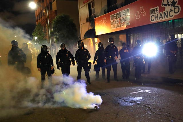 Police officers stand behind a canister of tear gas during a protest in Oakland, California on 29 May.