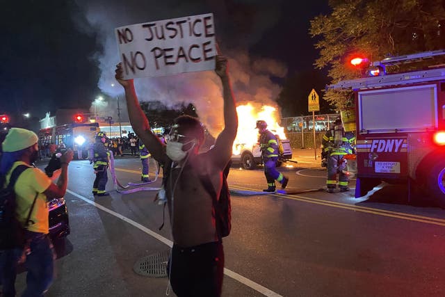 No justice, no peace: a protester stands in front of a burning police car in Brooklyn