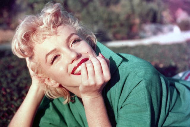 Marilyn Monroe poses for a portrait laying on the grass in 1954 in Palm Springs, California