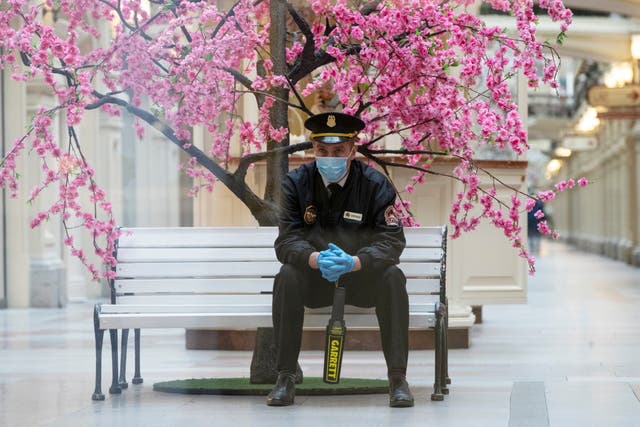 A security guard wearing a face mask and gloves waits for reopening of the GUM State Department store in Moscow