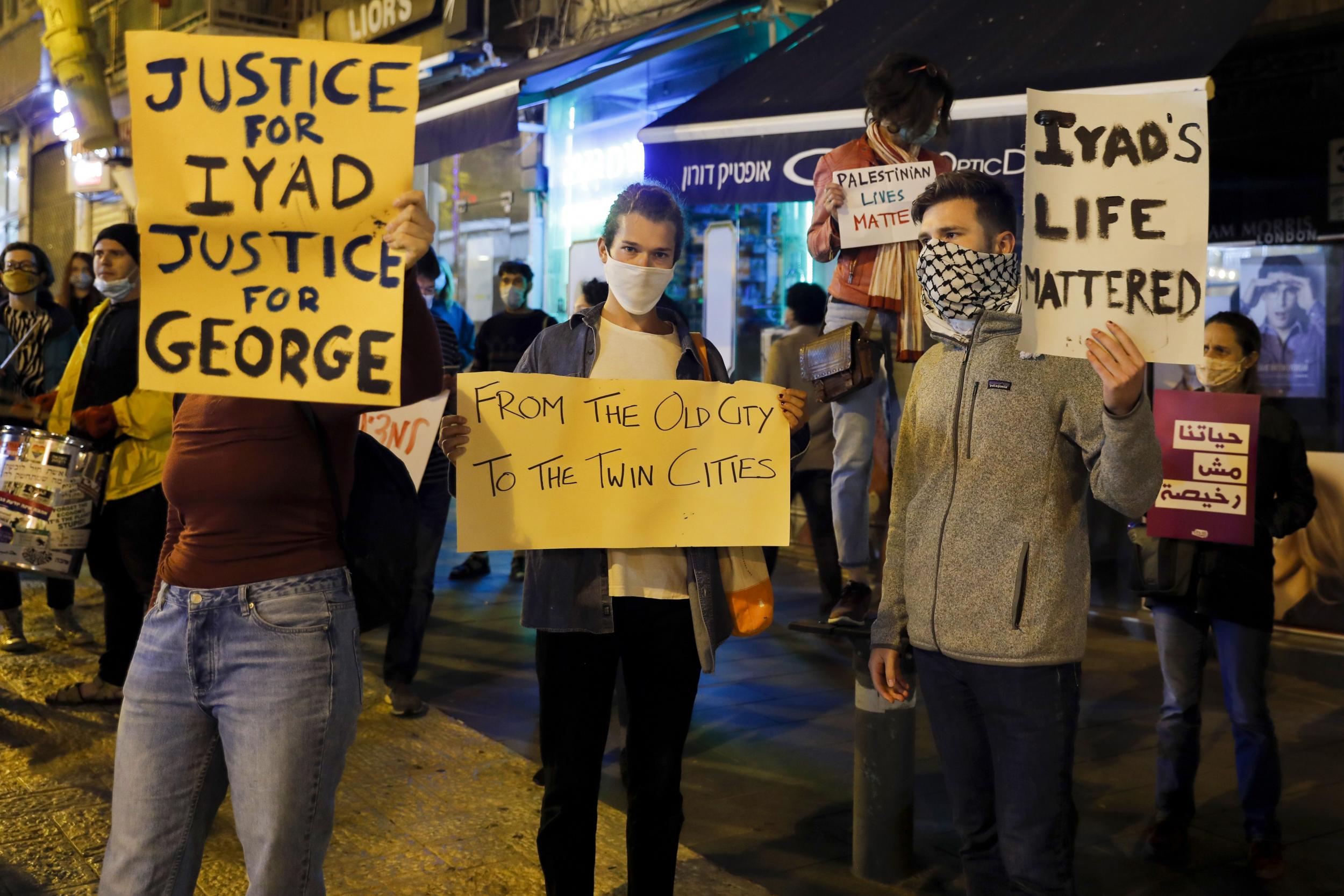 Israeli demonstrators carry placards during a demonstration condemning the shooting of Iyad Hallak, a disabled Palestinian man who was shot dead by Israeli police