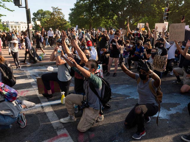 Protestors take a knee and raise their hands as they face riot police near the White House