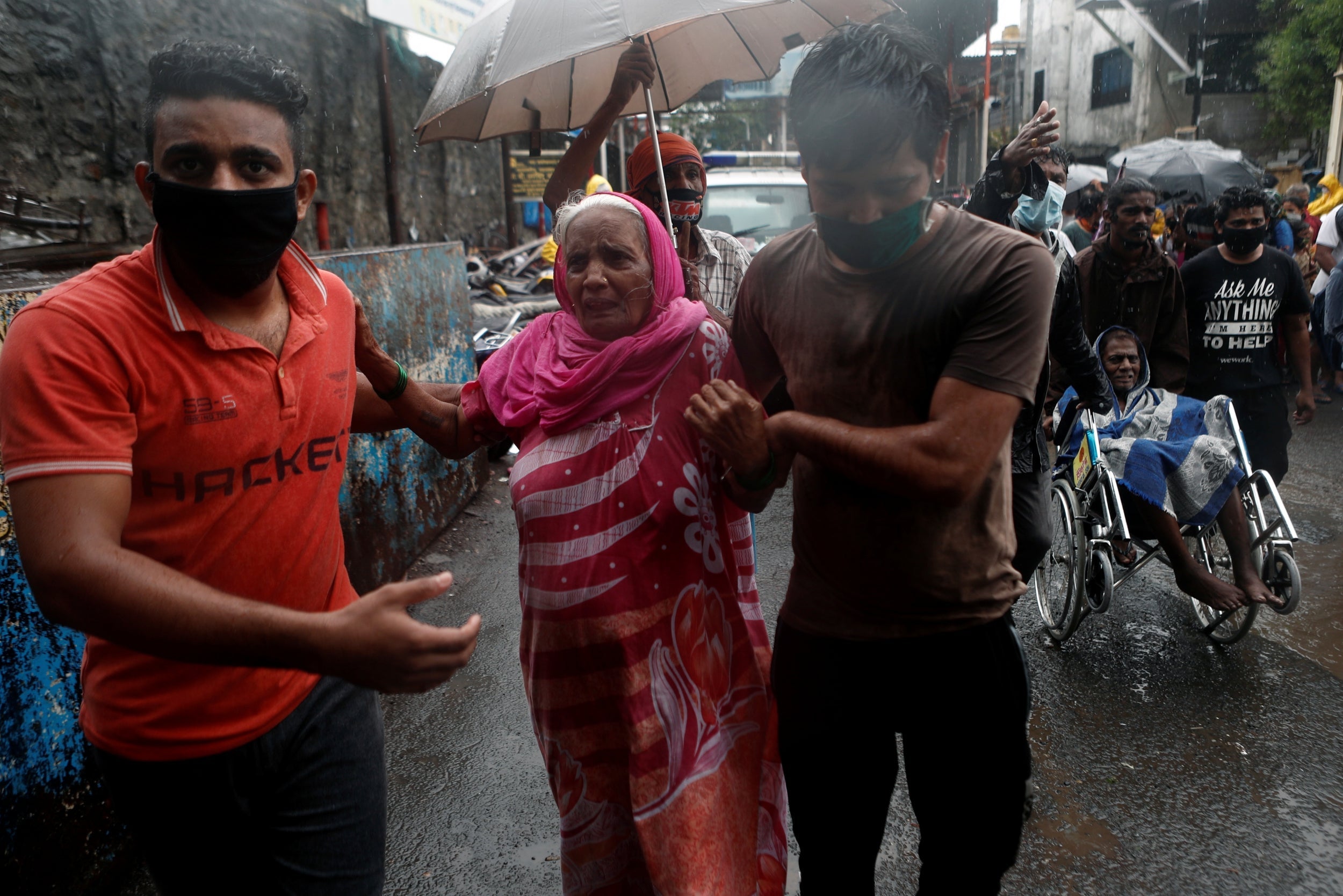 People help elderly citizens during an evacuation from a Mumbai slum