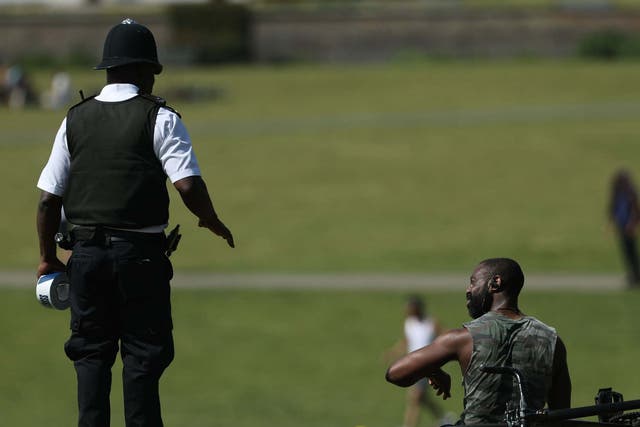 A police officer moves sunbathers in Greenwich Park, London, on 9 May