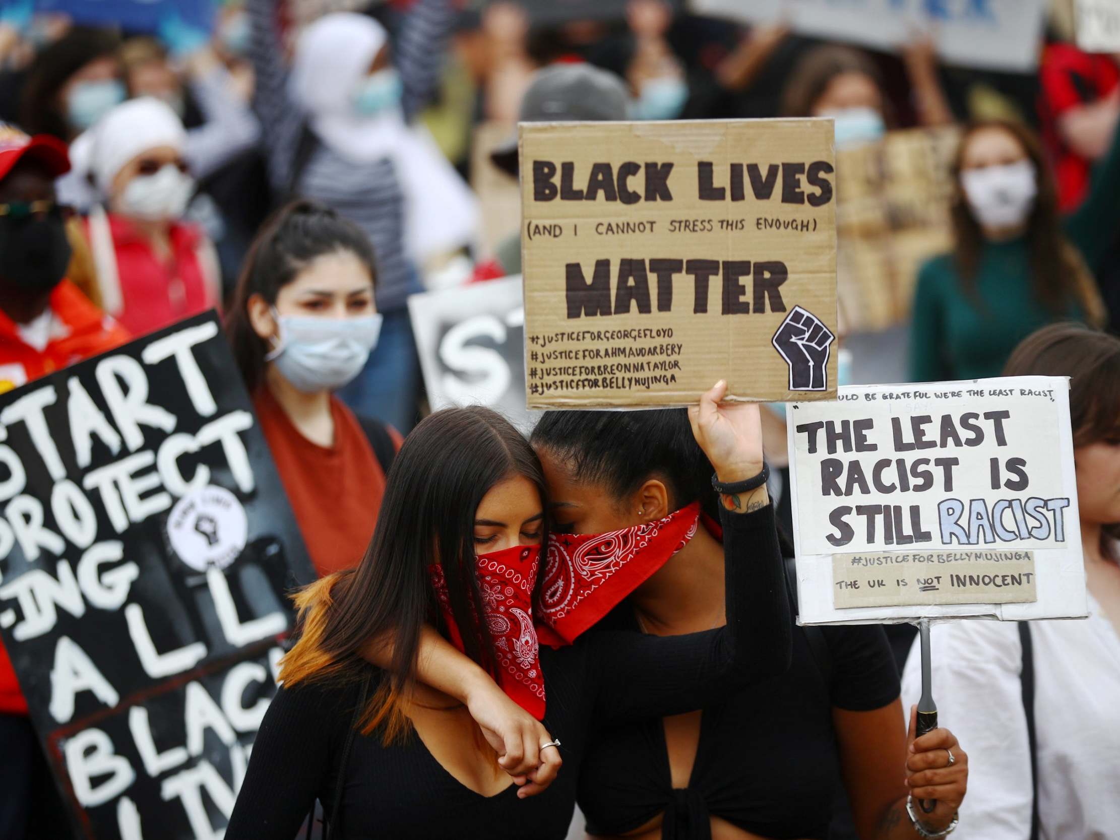People wearing face coverings react as they hold banners in Hyde Park during a "Black Lives Matter" protest following the death of George Floyd who died in police custody in Minneapolis