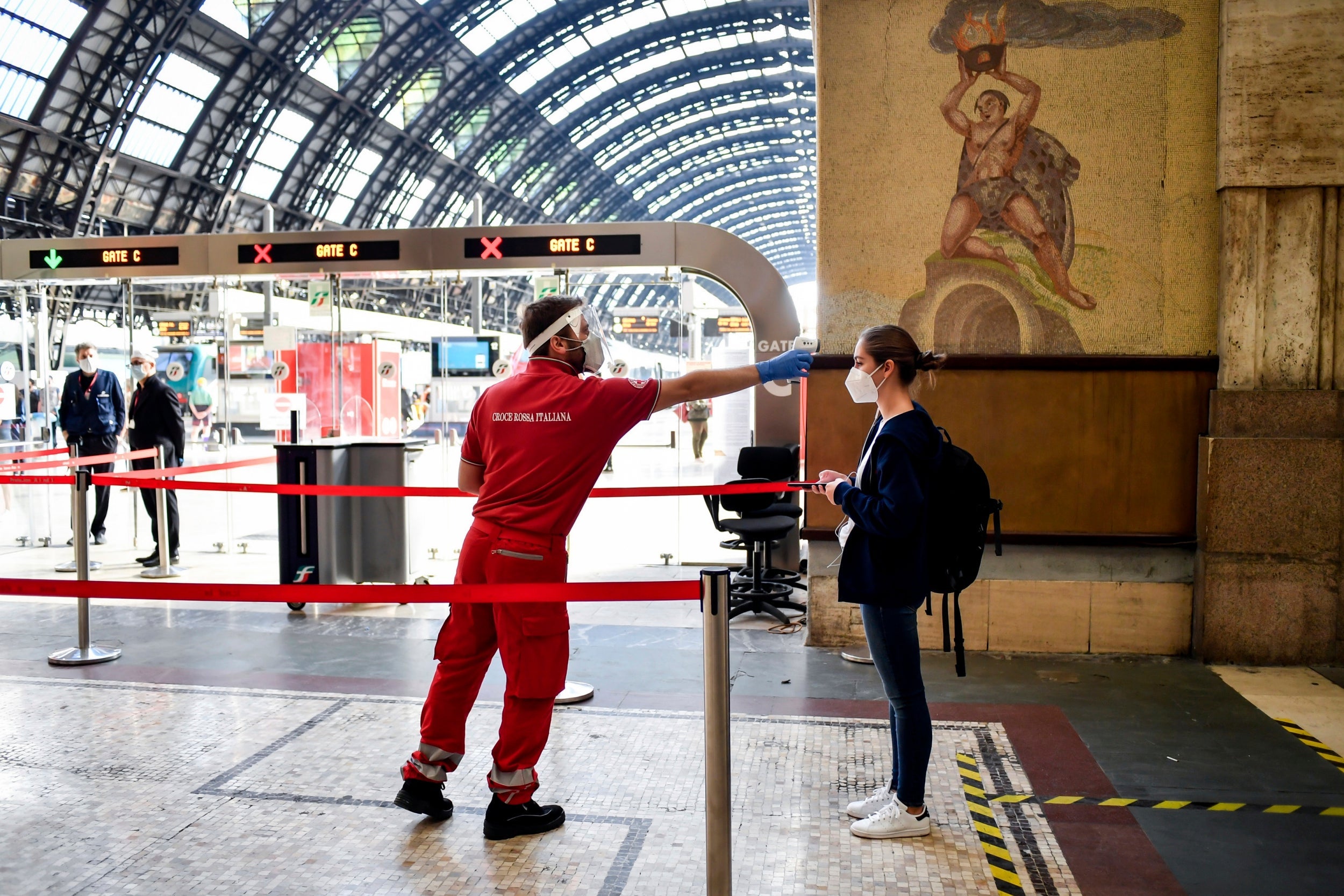 A passenger has her temperature taken to check for symptoms of Covid-19 before boarding a train to Milan’s Central Station,