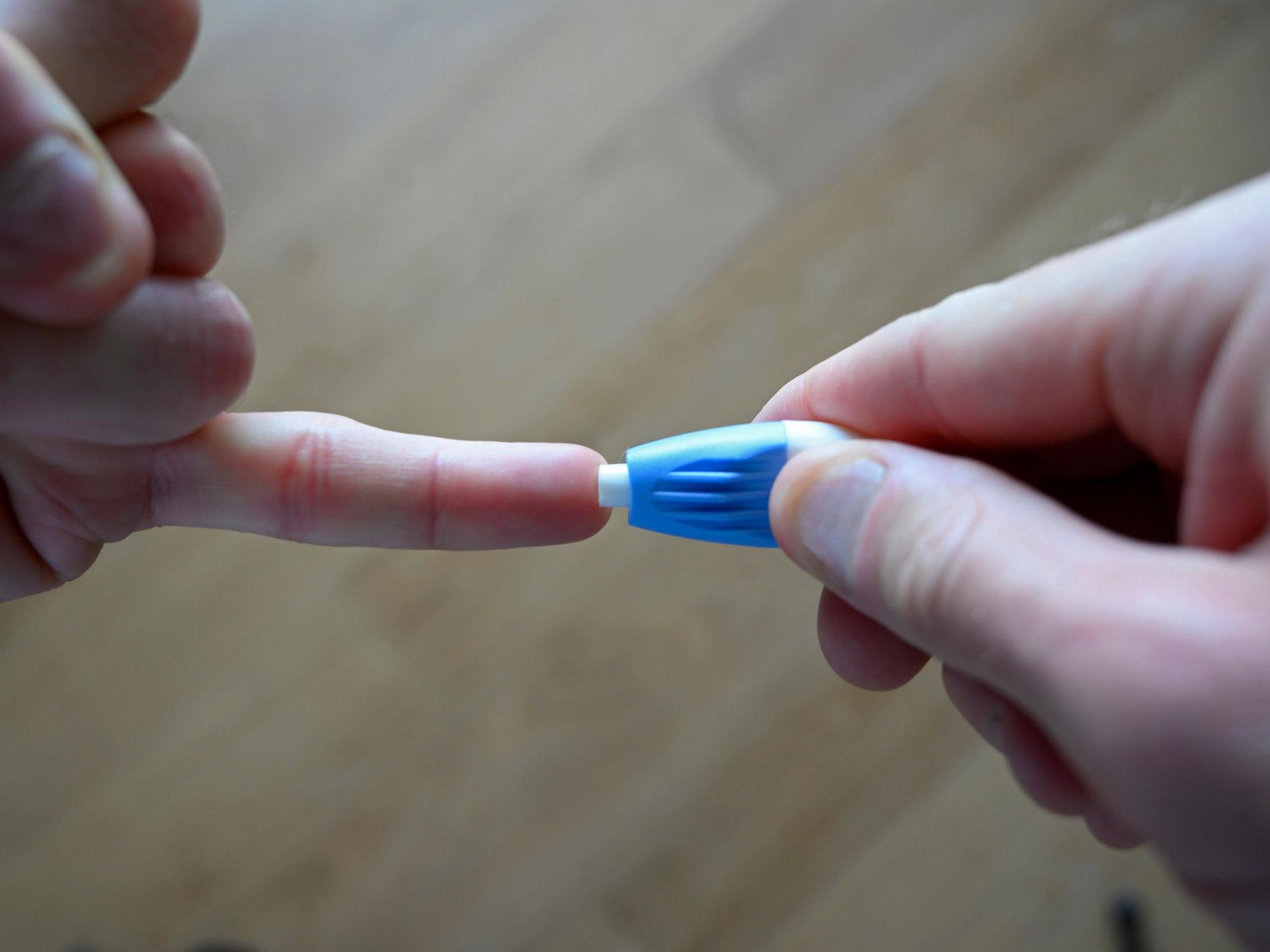 A man uses a lancet to prick the tip of his finger to provide blood for a coronavirus test in London on 28 May, 2020.