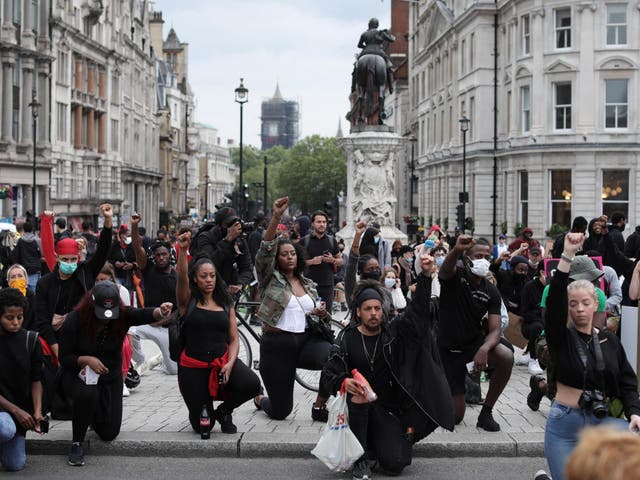 Protesters take the knee and raise clenched fists during a Black Lives Matter protest in Trafalgar Square