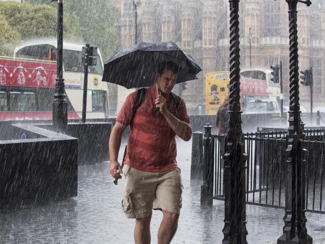 File image of man holding an umbrella as he walks through heavy rain in Westminster, London.
