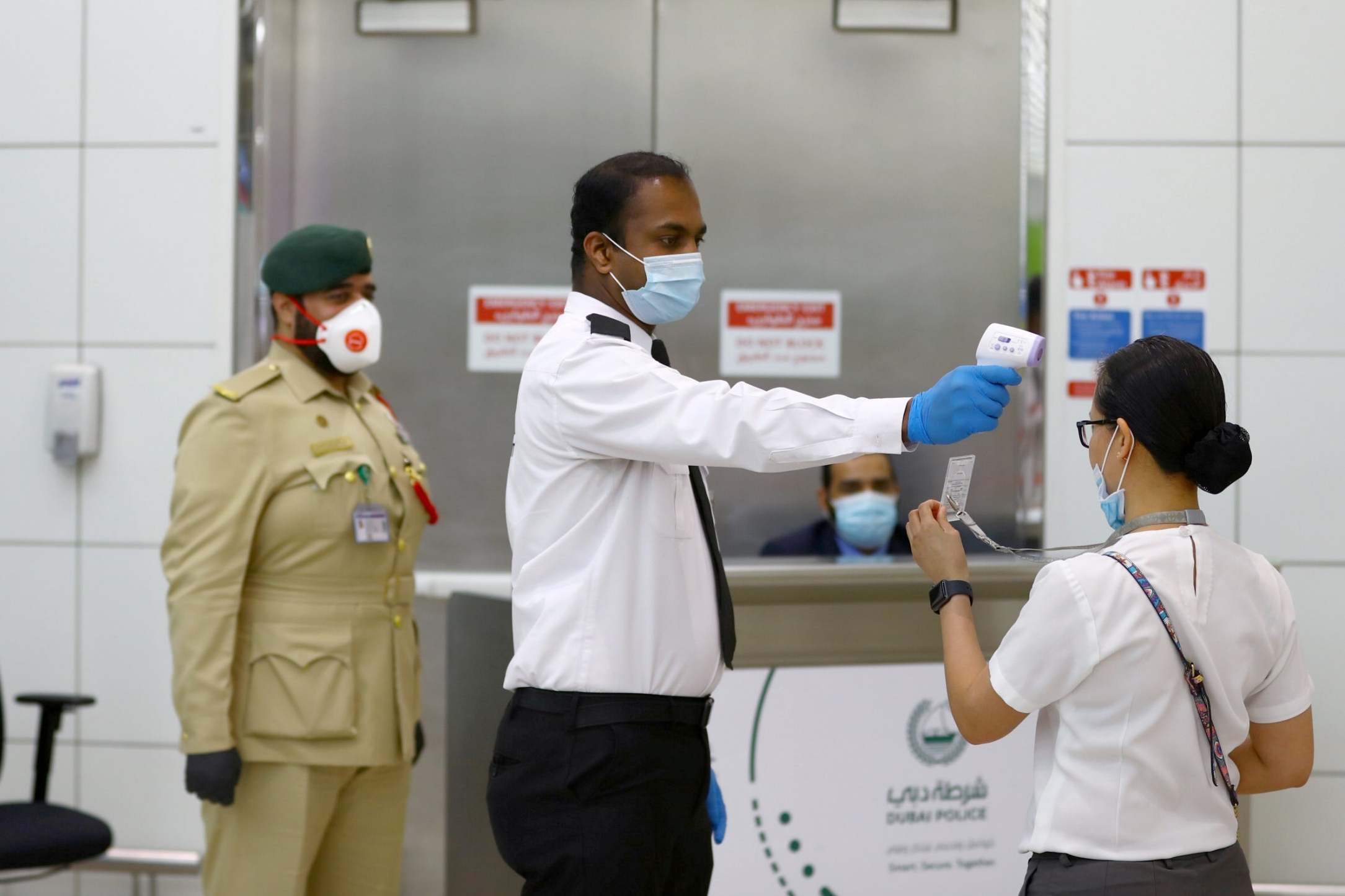Staff take a traveller’s temperature at Dubai International Airport