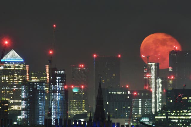 A full moon rising over the sky scrapers of London's Canary Wharf.