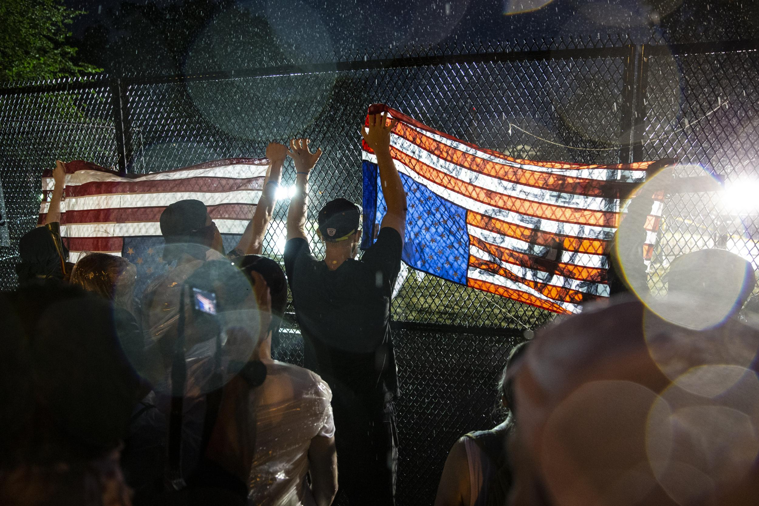 People gather at the fence that surrounds the White House in the rain for a peaceful protest against police brutality on Thursday