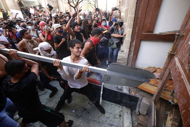Demonstrators smash a door during a protest following the death of a young man while in police custody in Guadalajara, Mexico