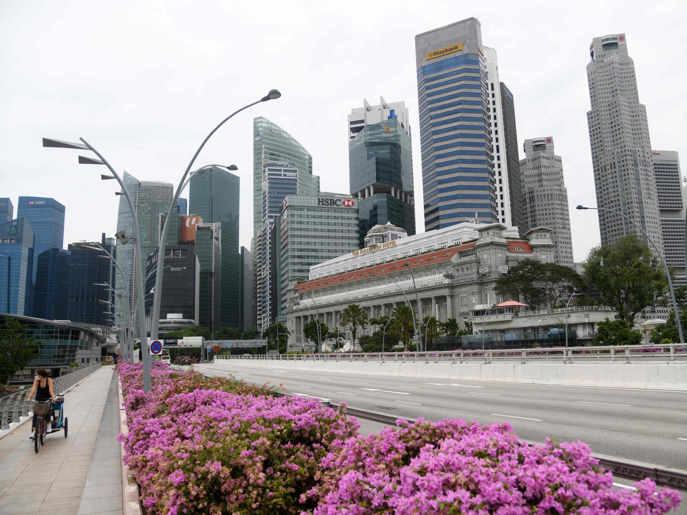 A woman cycles past the financial business district in Singapore, 27 May
