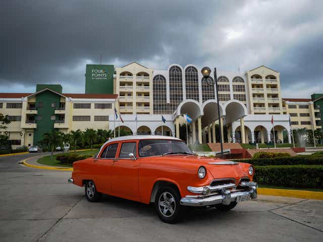 A vintage car passes in front of the Four Points by Sheraton hotel in Havana