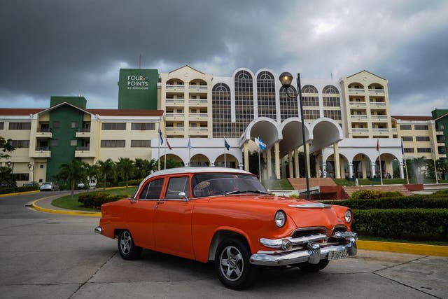 A vintage car passes in front of the Four Points by Sheraton hotel in Havana