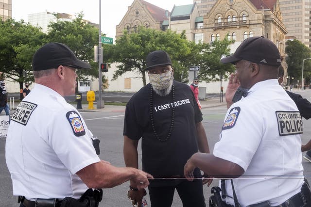 Columbus Police officers speak to a protester as thousands march towards the Statehouse in downtown Columbus, Ohio