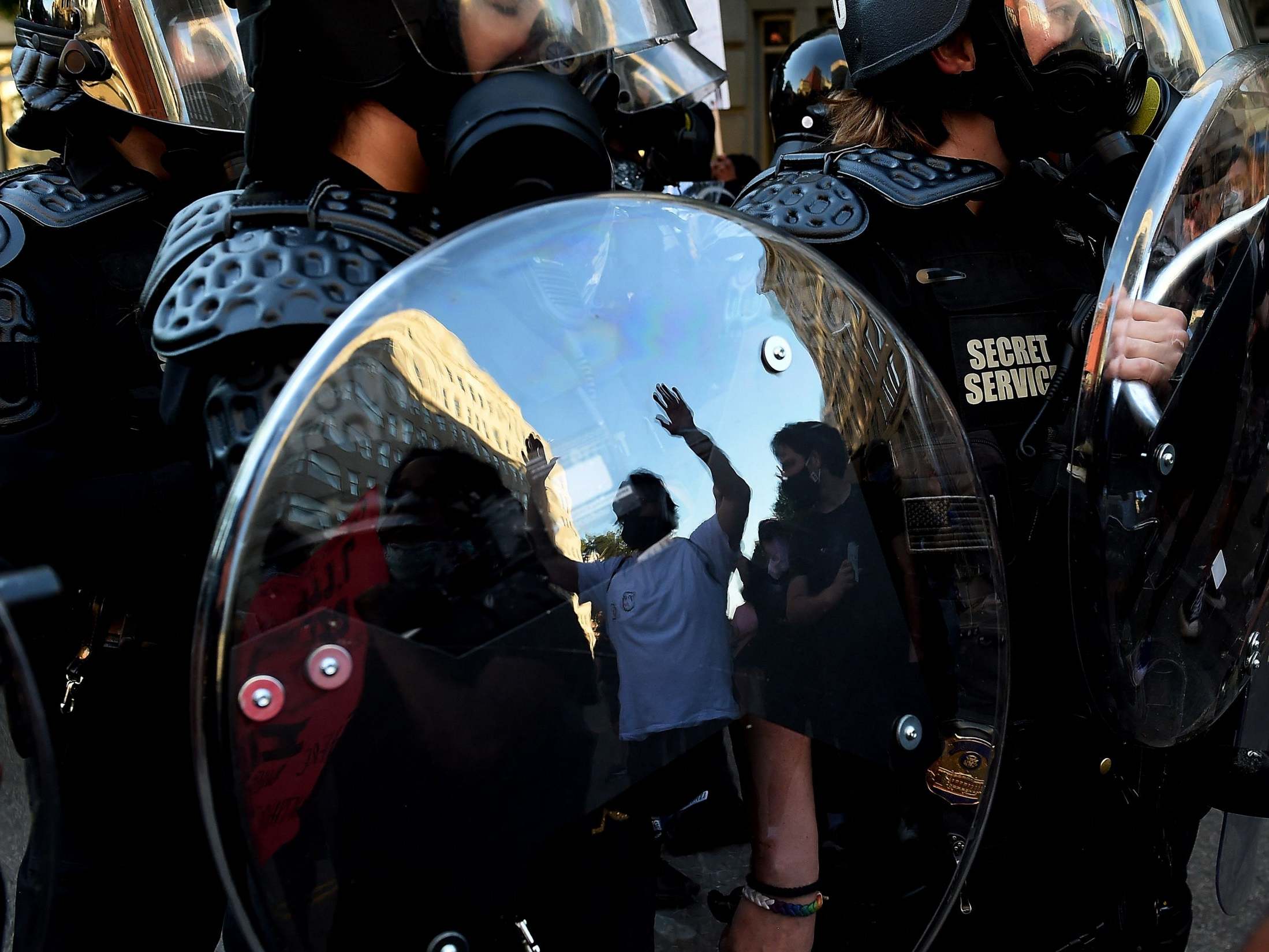 A protester is reflected in the shield of police officers during a demonstration against the death of George Floyd