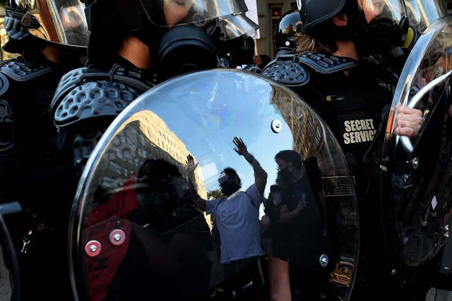 A protester is reflected in the shield of police officers during a demonstration against the death of George Floyd