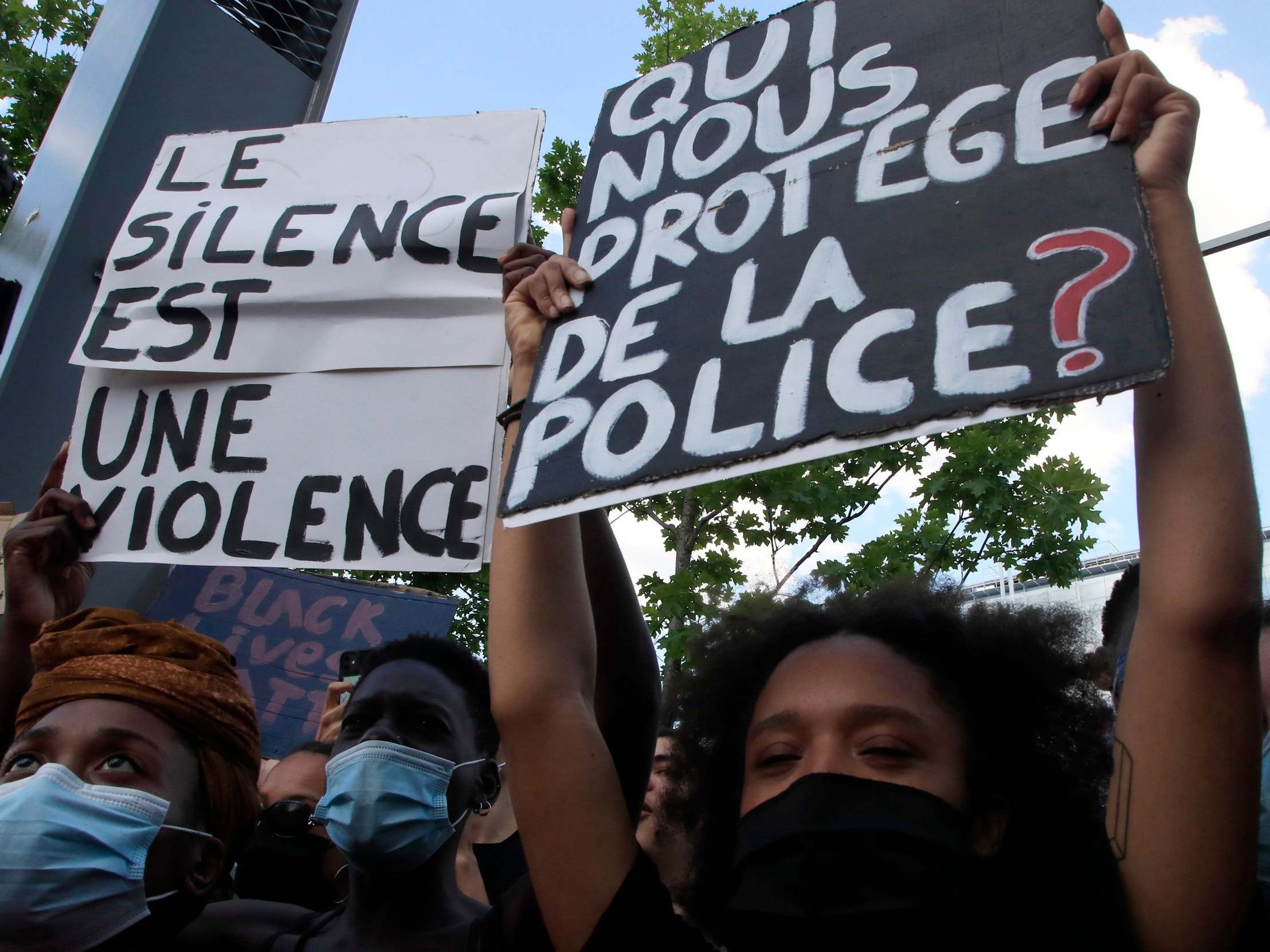 Protesters in Paris hold signs reading "Silence is violence" and "Who protects us from the police?"