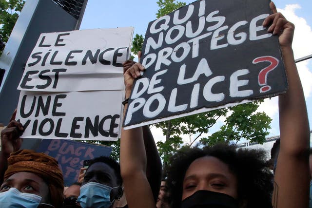 Protesters in Paris hold signs reading "Silence is violence" and "Who protects us from the police?"