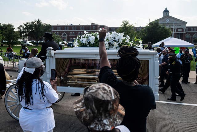 Mourners watch as the casket of George Floyd is carried by a white horse-drawn carriage to his final resting place at the Houston Memorial Gardens cemetery in Pearland, Texas on June 9, 2020.