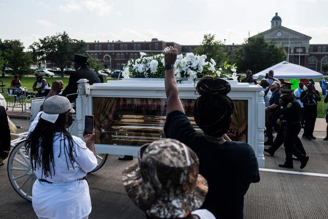 Mourners watch as the casket of George Floyd is carried by a white horse-drawn carriage to his final resting place at the Houston Memorial Gardens cemetery in Pearland, Texas on June 9, 2020.