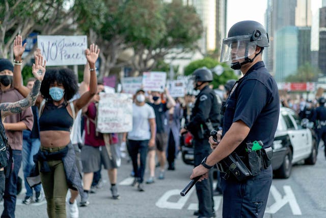Protesters march past LAPD officers during a demonstration over the death of George Floyd