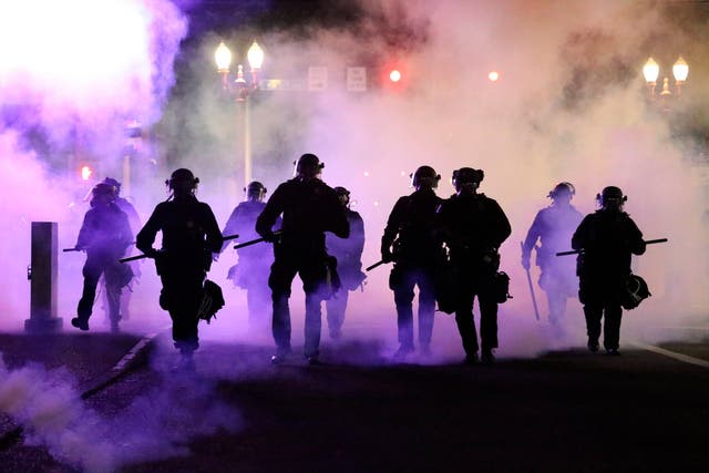 Police officers in Portland march towards protesters after firing teargas