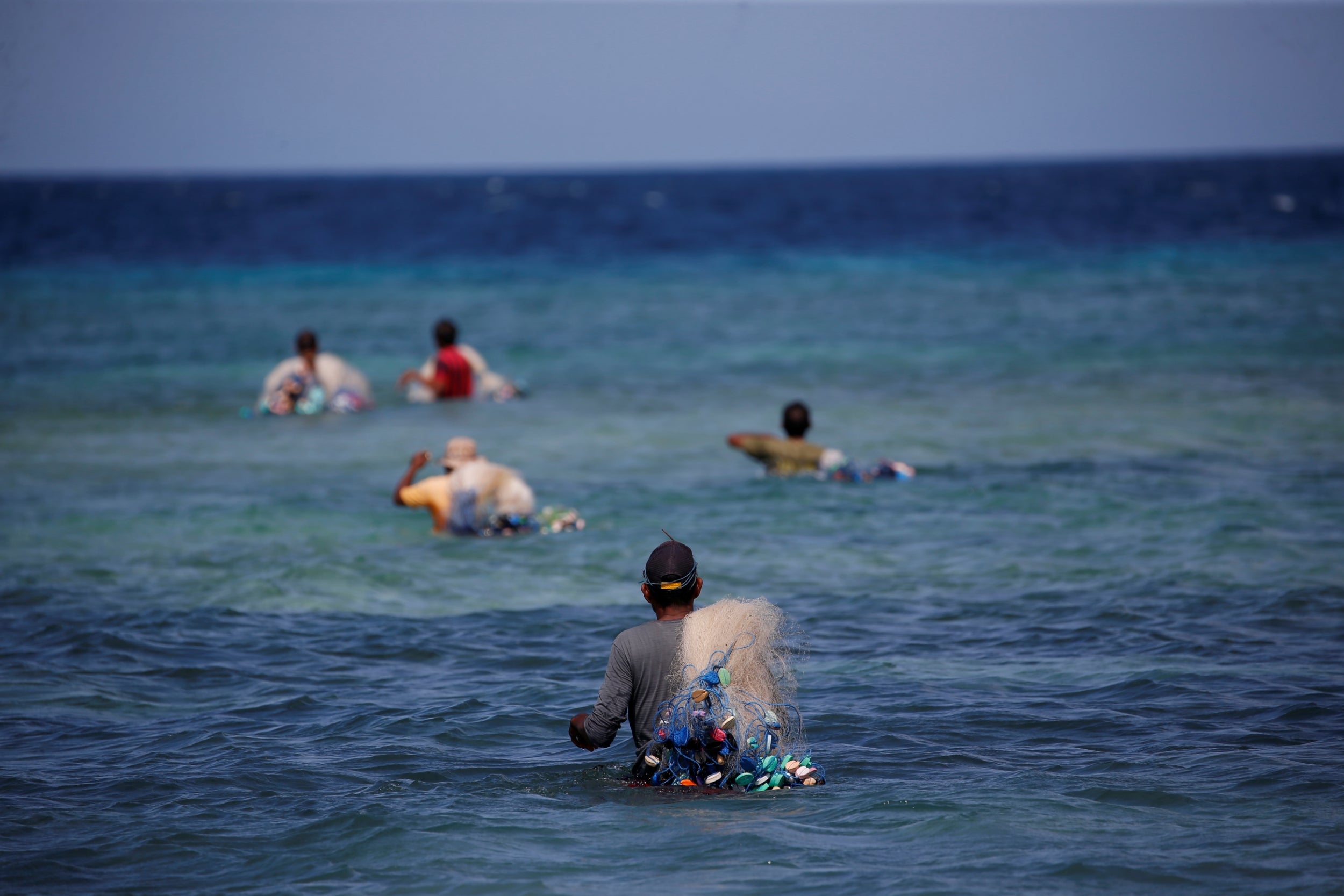 Ndelu Ndaha carries his net through the sea as he fishes on Puru Kambera beach