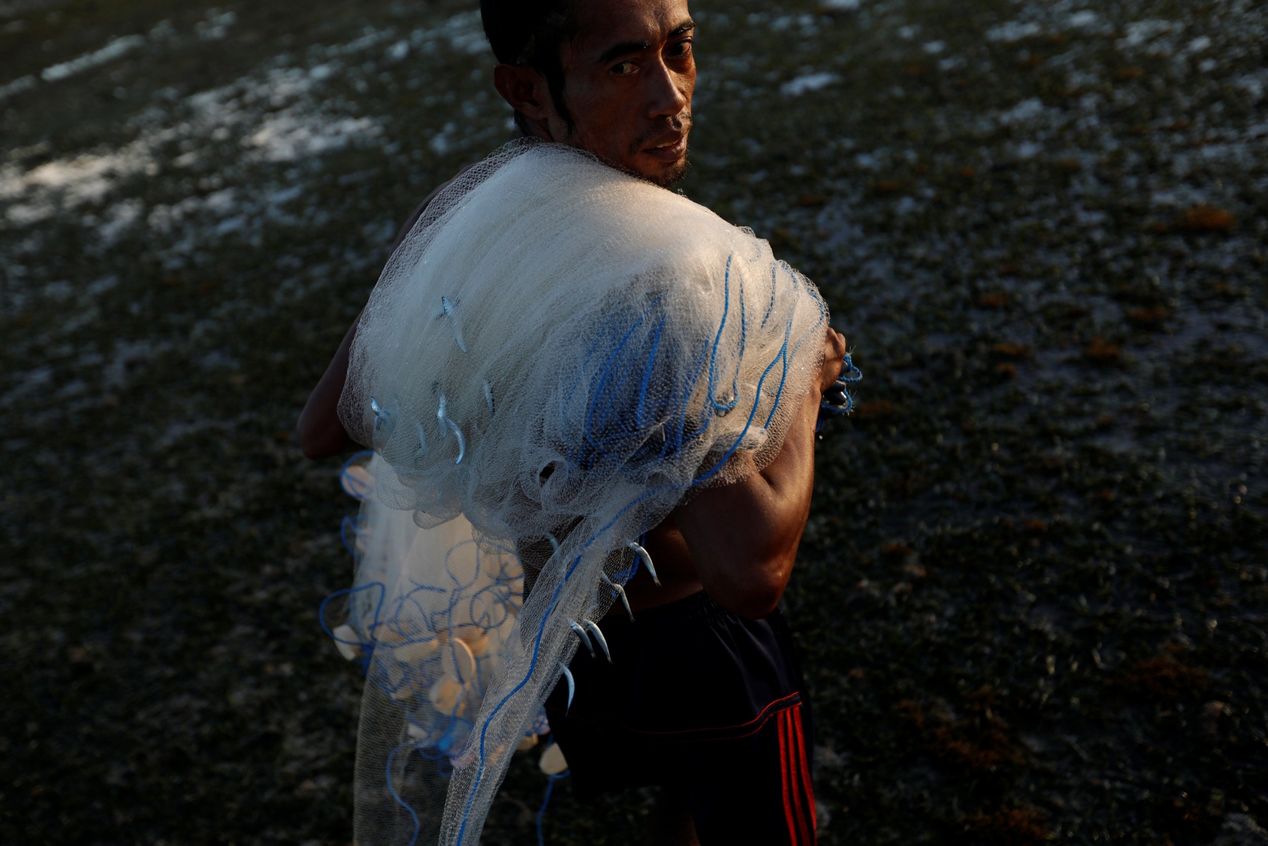 Julkarnaen Mansyur, a fisherman from Waingapu, carries his net back to the shore