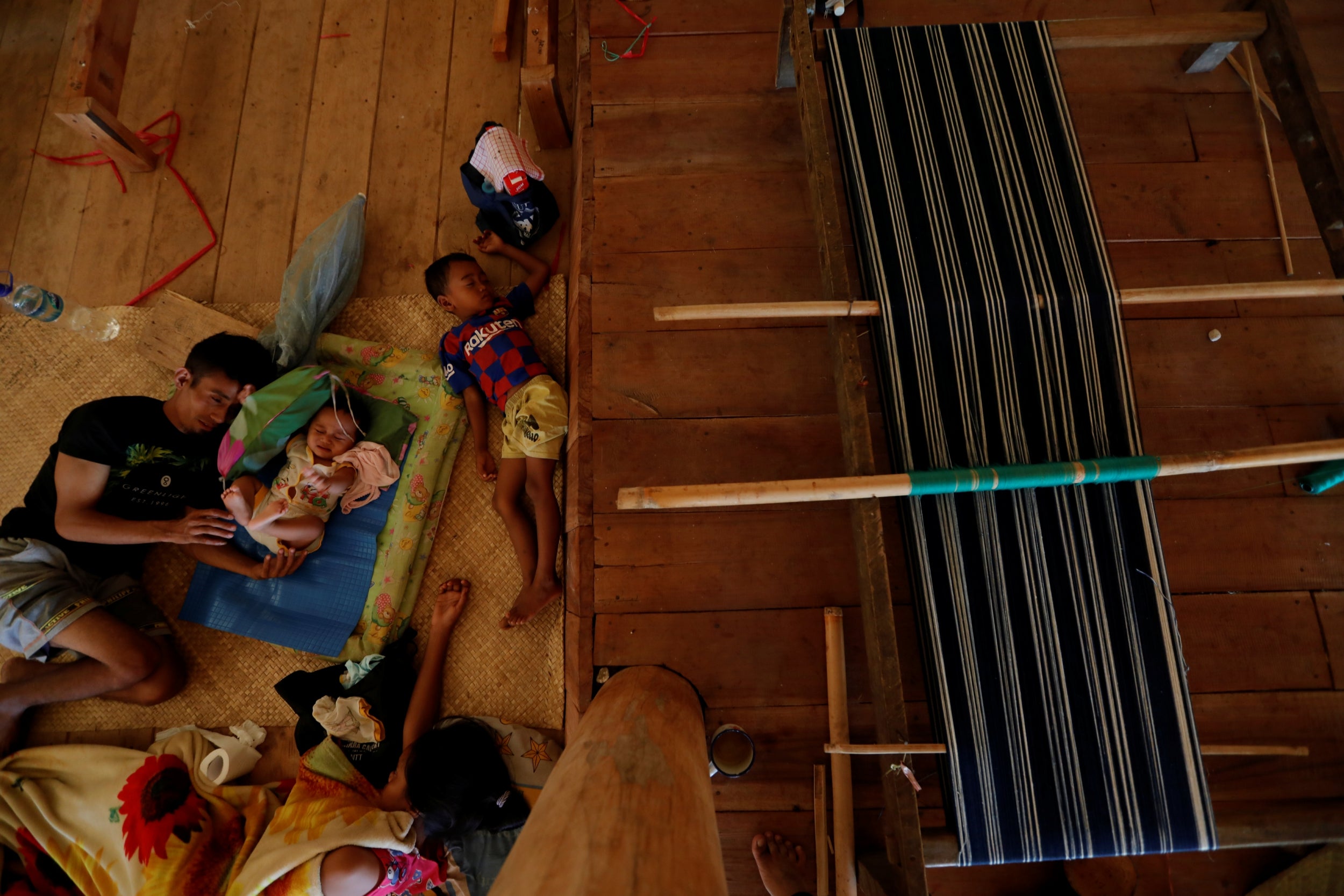 Andreas Windi Mbaku Rawa rests with his children at his parent’s weaving house