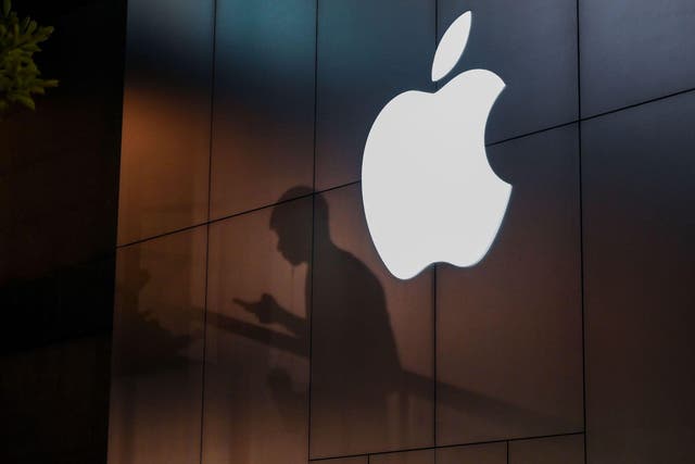 The shadow of a man is cast on the wall of an Apple store as he uses his mobile phone in Beijing on August 26, 2019