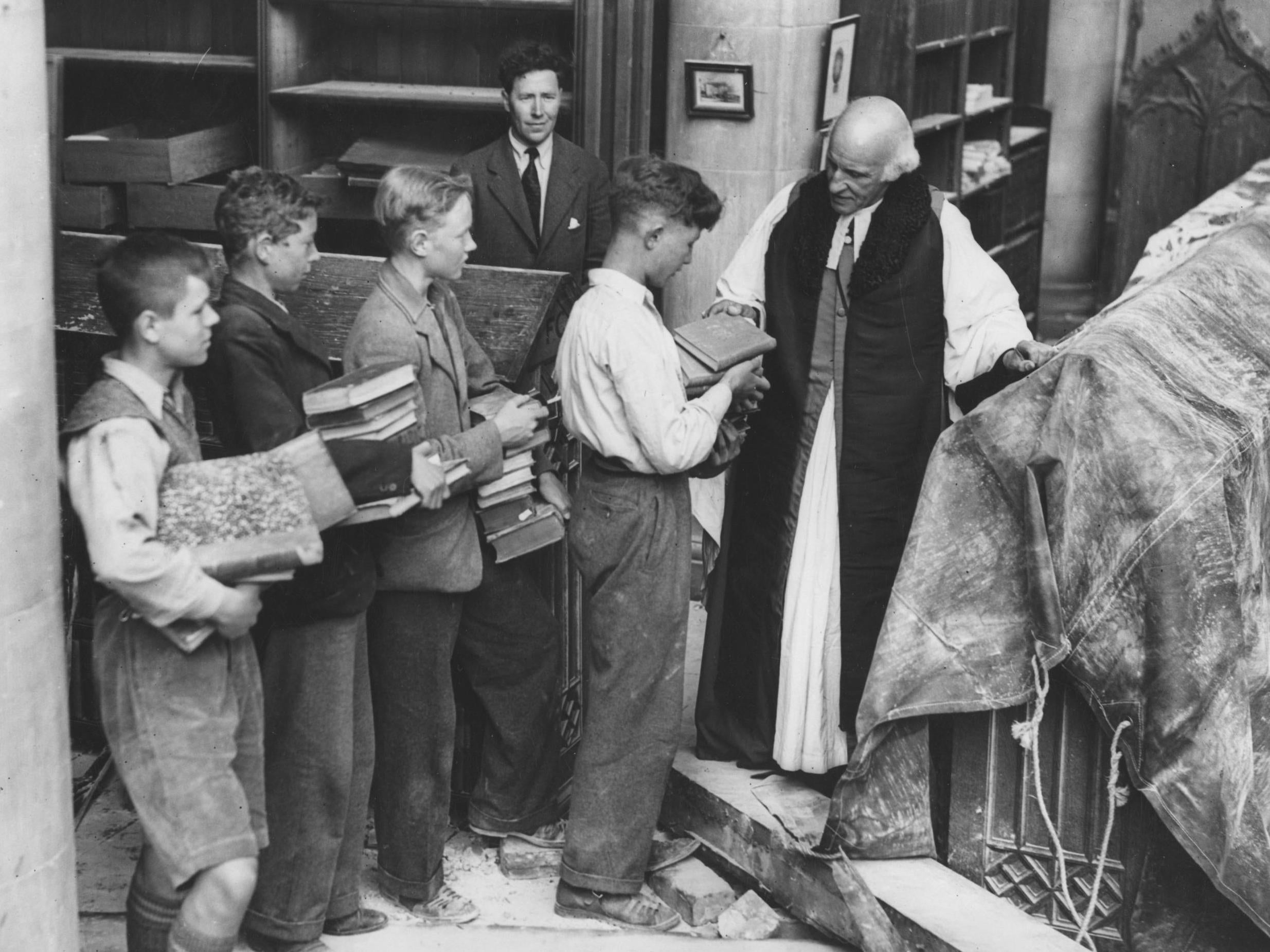 Dean of Canterbury Cathedral checks salvaged books after the cathedral was damaged