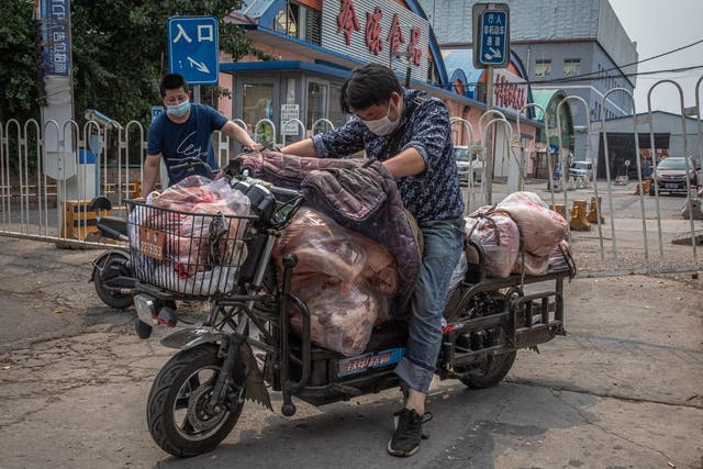 Men in face masks load a scooter with meat after the Beijing market was closed