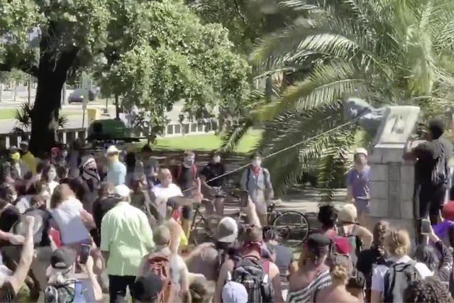 In this frame grab from video posted on Twitter, protesters bring down a bust of slave owner John McDonogh on Saturday, 13 June, 2020, at Duncan Plaza in New Orleans