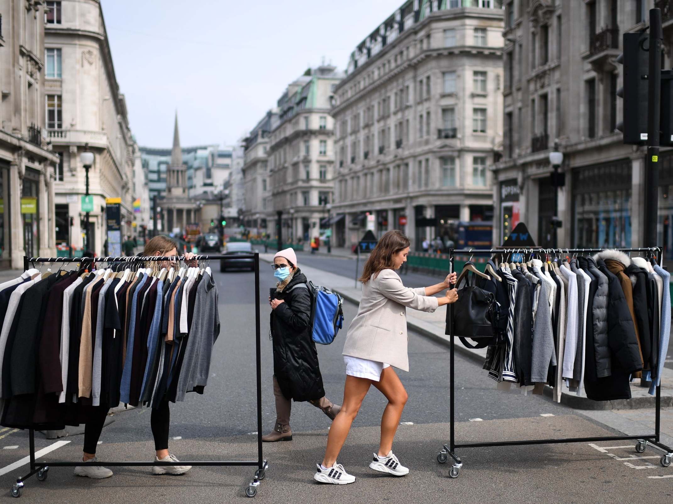 Retail workers move rails of clothes between stores on Oxford Street ahead of reopening yesterday