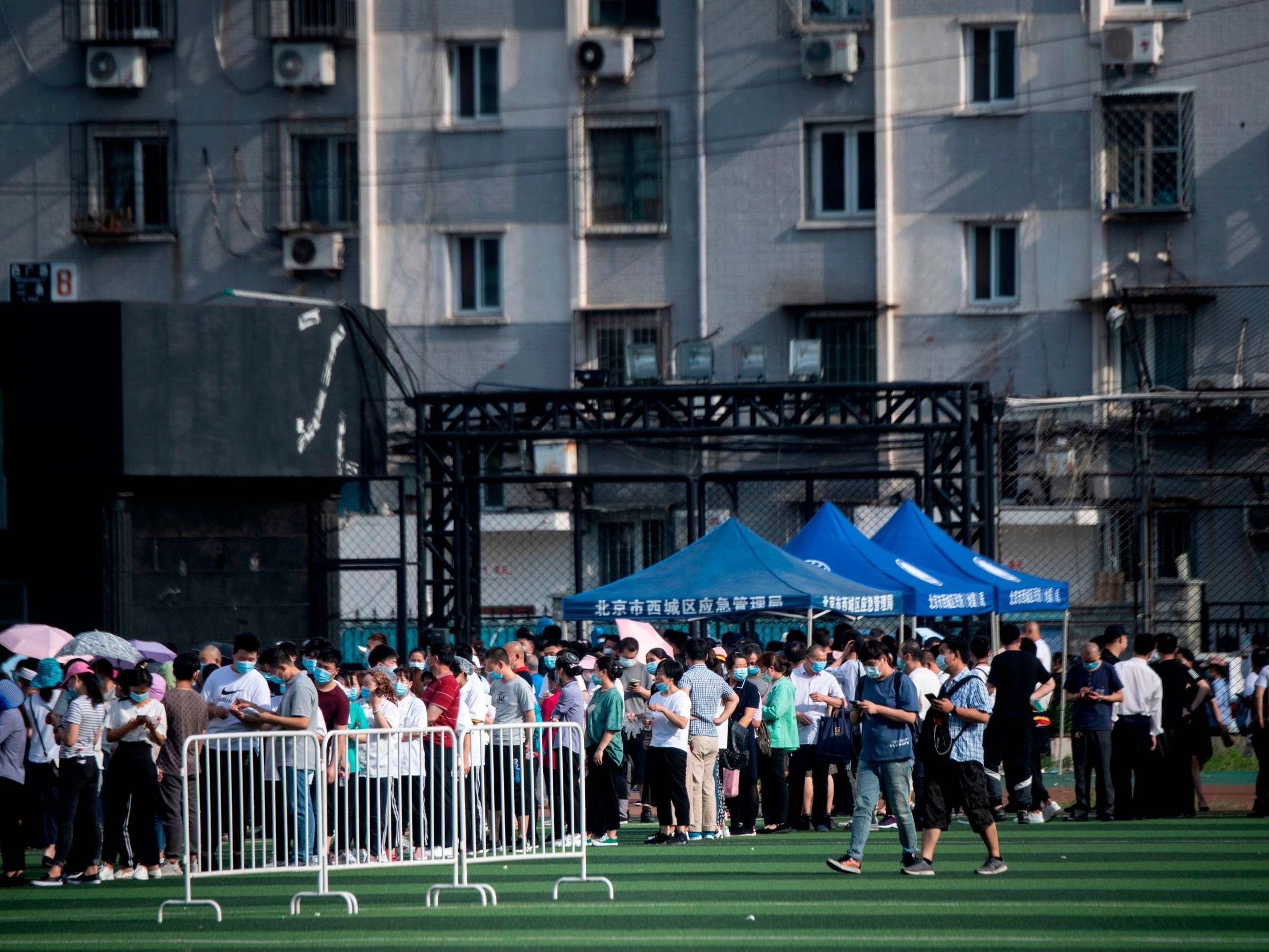 People who live near or have visited the Xinfadi market queue for testing at the Guang'an sports centre in Beijing on 16 June 2020.