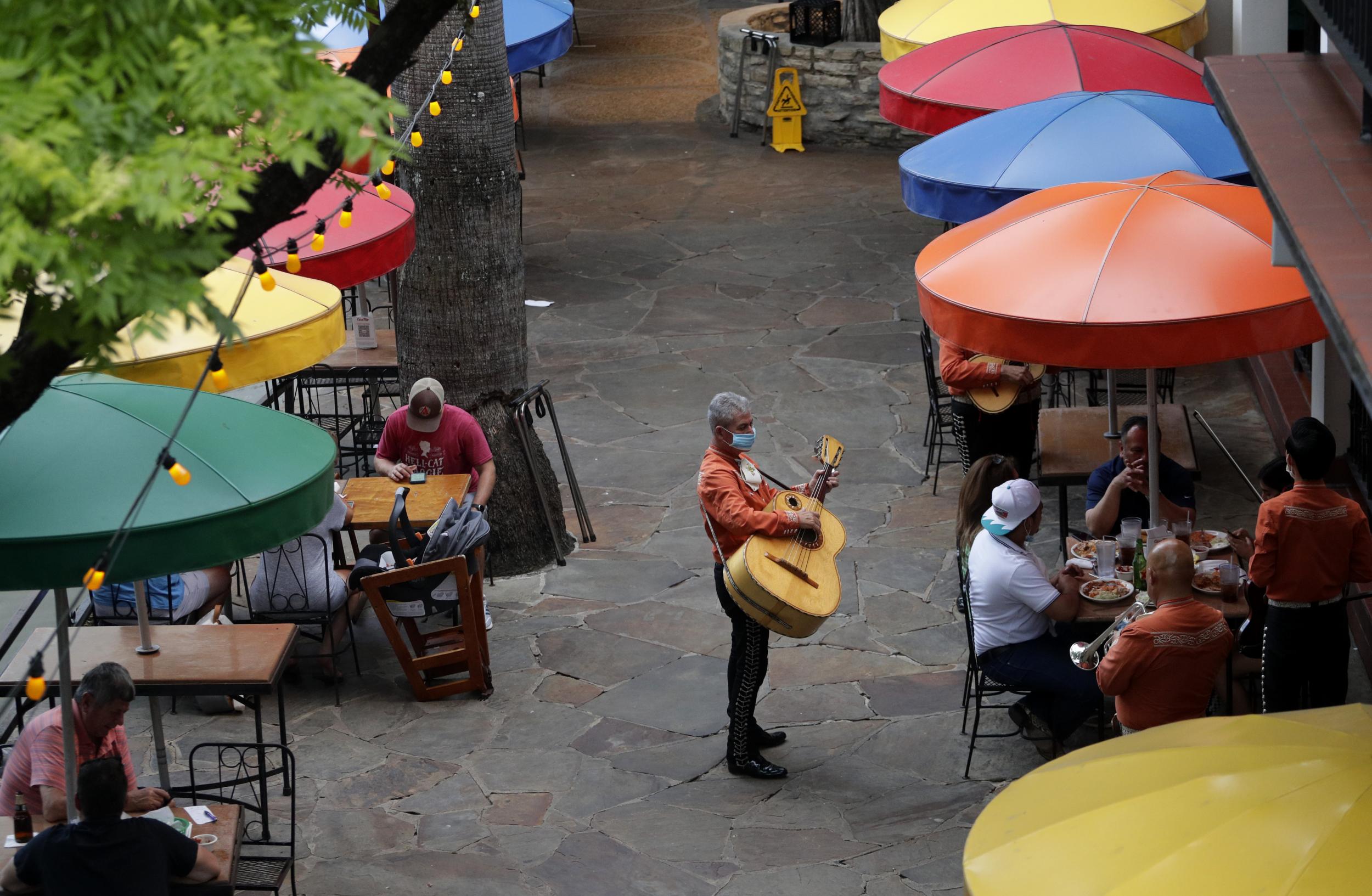 Mariachi musicians, wearing face masks, play for diners at a restaurant that has reopened to 50 per cent capacity on the River Walk in San Antonio, Wednesday, May 27, 2020.