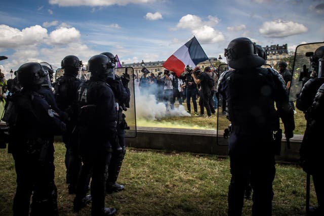 A protester holding a French flag faces police forces during a protest against goverment policies and demand better employment conditions for hospital workers in Paris, France