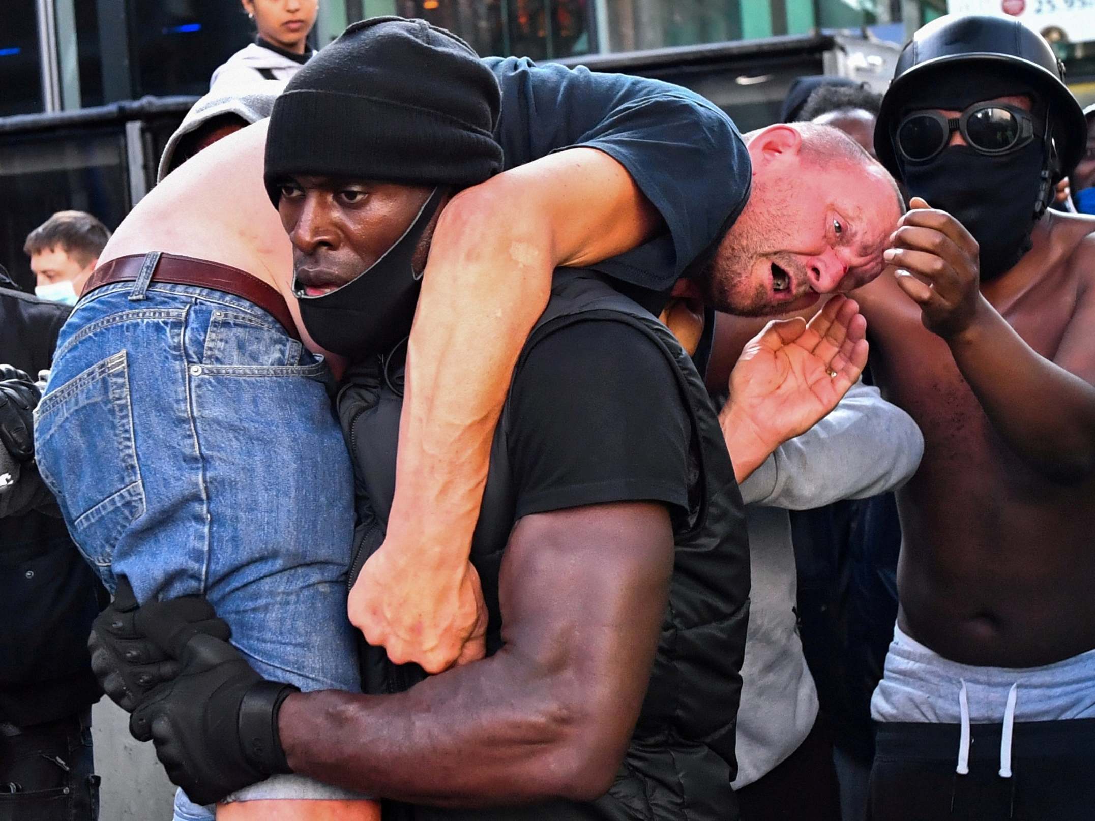 Protester Patrick Hutchinson carries an injured counter-protester to safety during Black Lives Matter demonstrations in central London, 13 June 2020.