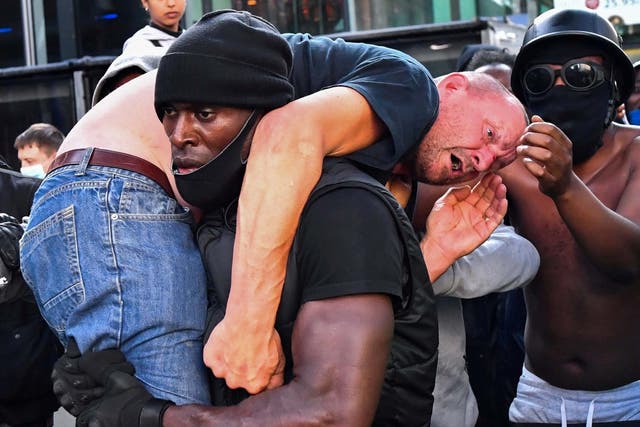 Protester Patrick Hutchinson carries an injured counter-protester to safety during Black Lives Matter demonstrations in central London, 13 June 2020.
