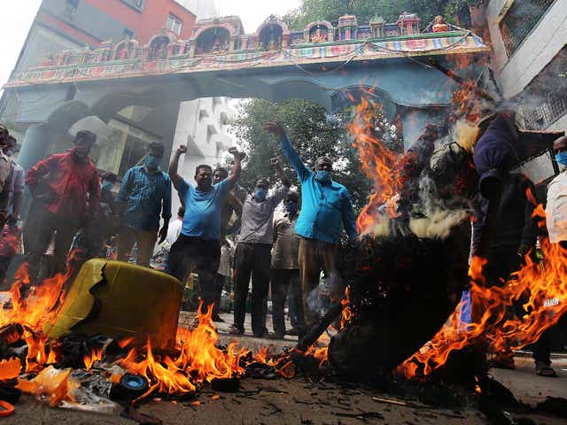 Activists burn photos of Chinese President Xi Jinping during a protest in Bangalore