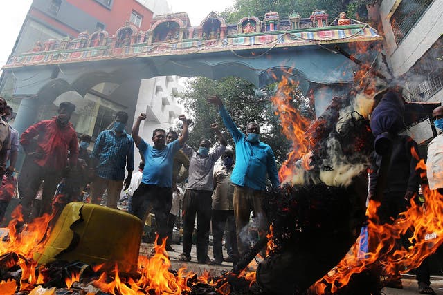Activists burn photos of Chinese President Xi Jinping during a protest in Bangalore