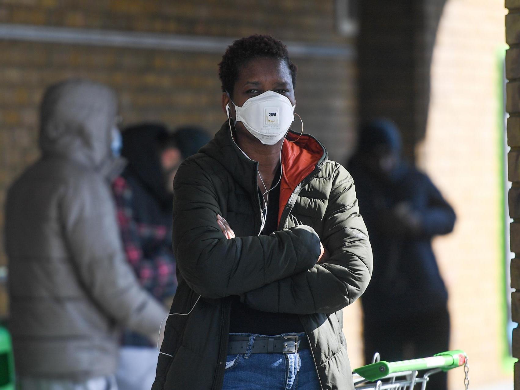 A woman wearing a face mask queues to enter an Asda supermarket on 22 March 2020 in London, England