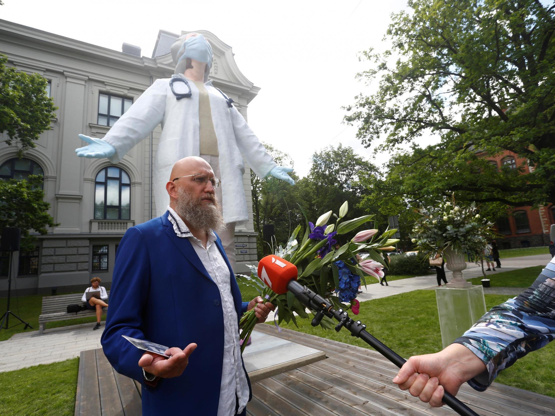 Sculptor Aigars Bikse speaks to the media next to his six-meter tall statue devoted to medics for their work during the coronavirus disease outbreak in Riga