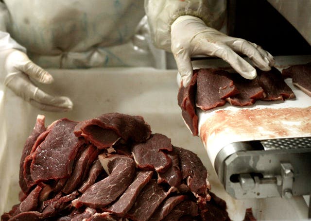 A butcher chops pieces of meat at an abattoir